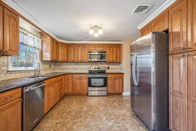 kitchen with a sink, visible vents, appliances with stainless steel finishes, backsplash, and brown cabinetry