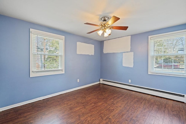 spare room with a healthy amount of sunlight, baseboards, a baseboard heating unit, and wood finished floors