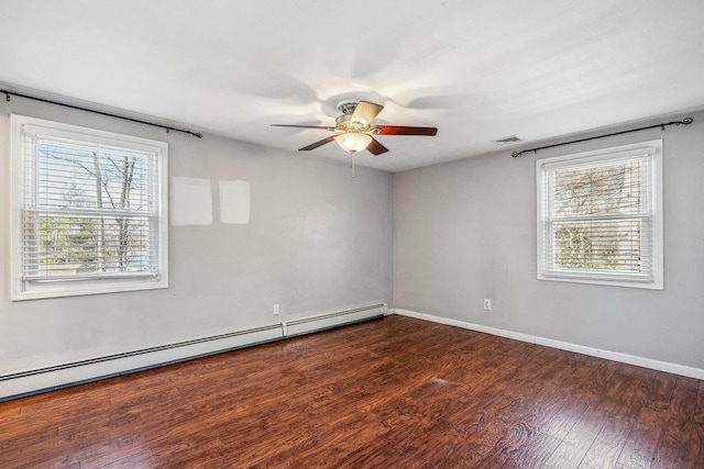 empty room with a wealth of natural light, visible vents, baseboard heating, and wood finished floors