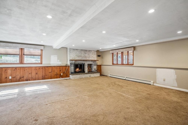 unfurnished living room featuring a brick fireplace, a baseboard heating unit, a wealth of natural light, and recessed lighting