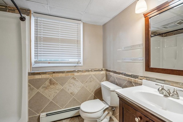 full bath featuring a baseboard radiator, visible vents, toilet, vanity, and a drop ceiling