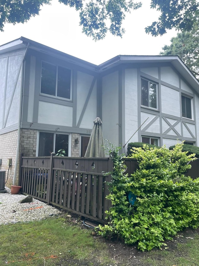 view of home's exterior featuring brick siding, central AC, and stucco siding