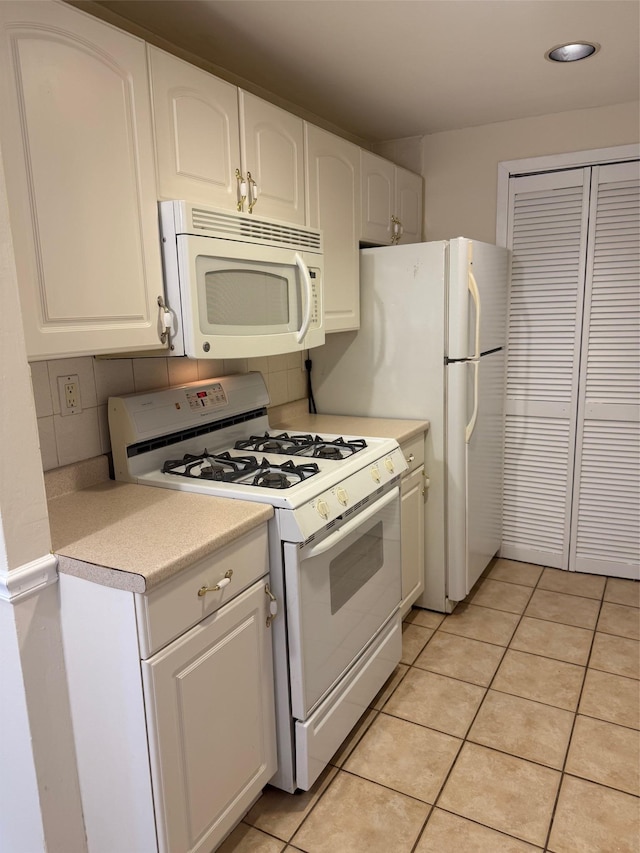 kitchen with light tile patterned flooring, white appliances, white cabinetry, light countertops, and decorative backsplash