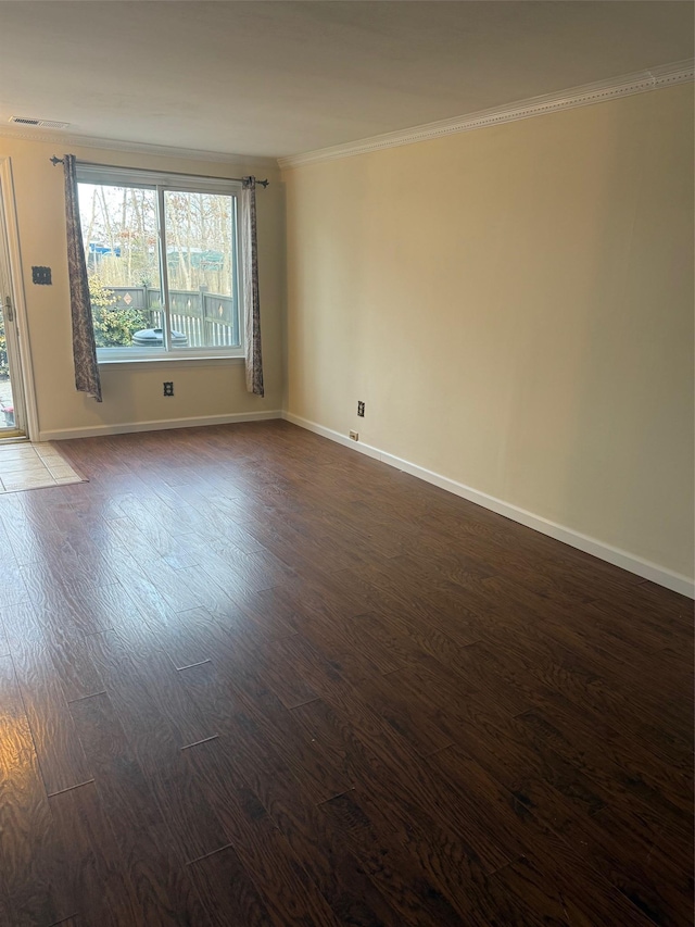 empty room featuring dark wood finished floors, crown molding, and baseboards