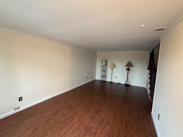 empty room with dark wood-style floors, baseboards, visible vents, and ornamental molding