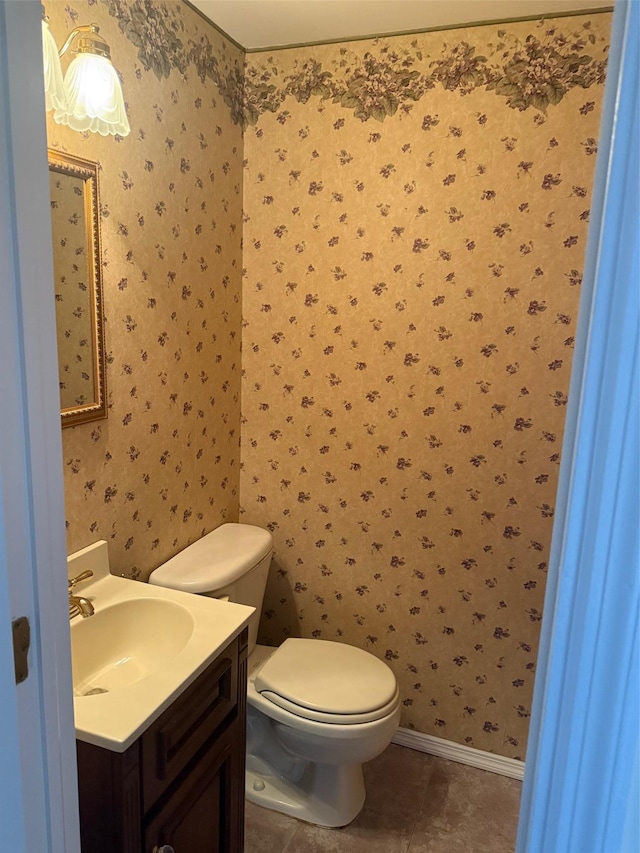 half bath with tile patterned floors, vanity, toilet, and wallpapered walls