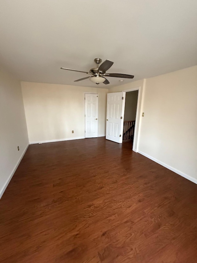 spare room with dark wood finished floors, a ceiling fan, and baseboards