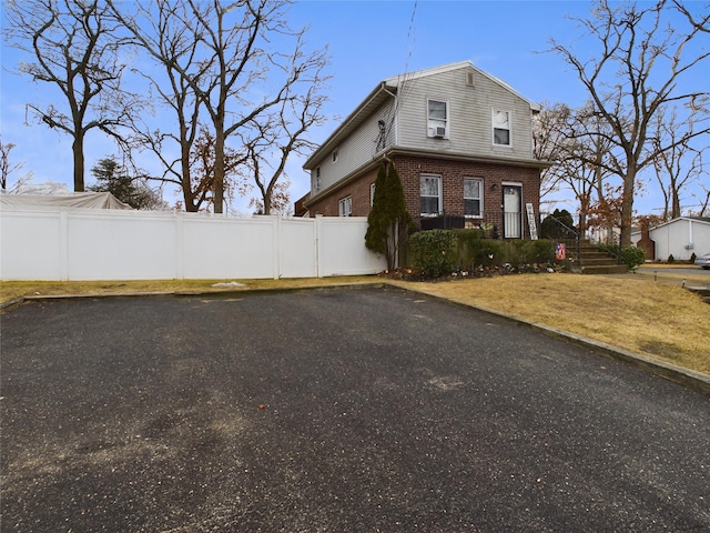 view of property exterior featuring brick siding, fence, and a lawn