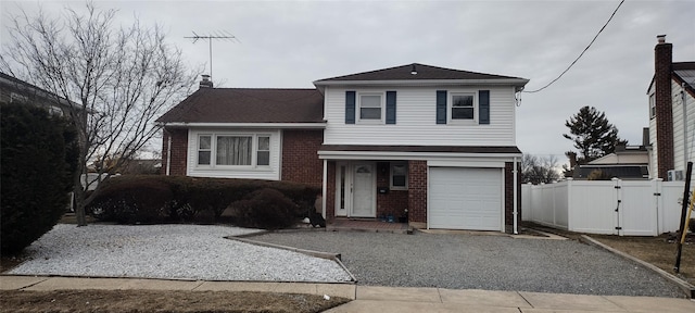 tri-level home featuring a garage, a chimney, gravel driveway, fence, and brick siding