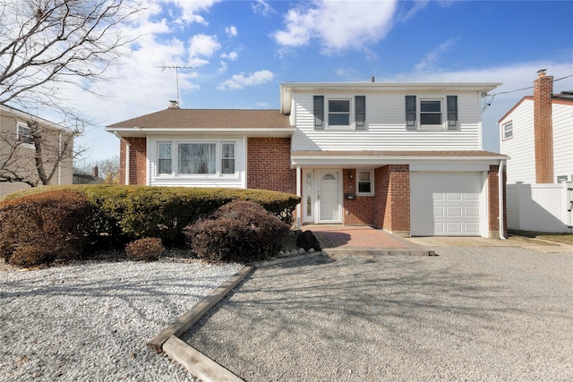 split level home with brick siding, an attached garage, gravel driveway, and fence