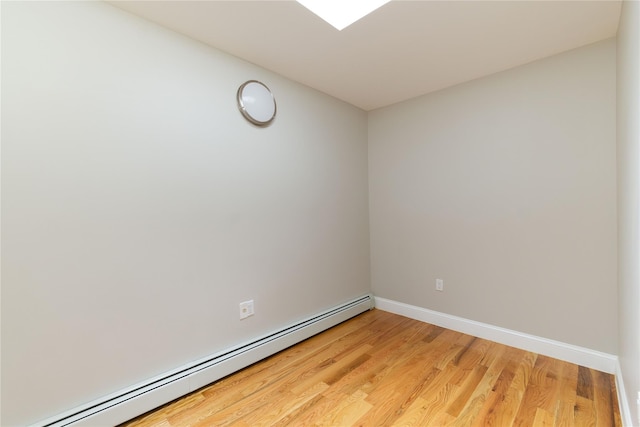 empty room with a baseboard heating unit, light wood-style flooring, and baseboards