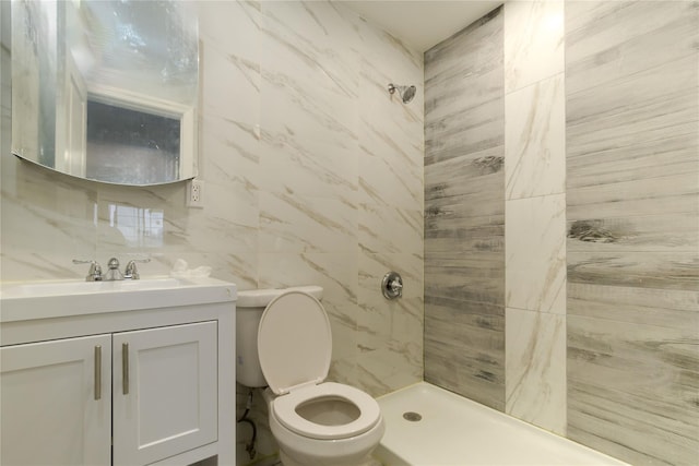 full bathroom with a stall shower, vanity, toilet, and tile walls