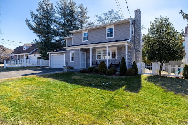 traditional home with covered porch, fence, driveway, a chimney, and a front yard