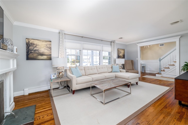 living area featuring ornamental molding, a premium fireplace, wood finished floors, and visible vents