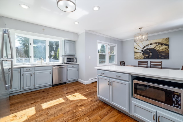 kitchen with stainless steel appliances, gray cabinets, a chandelier, and ornamental molding