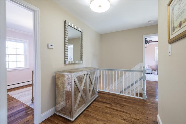 corridor with a baseboard radiator, wood finished floors, an upstairs landing, and baseboards