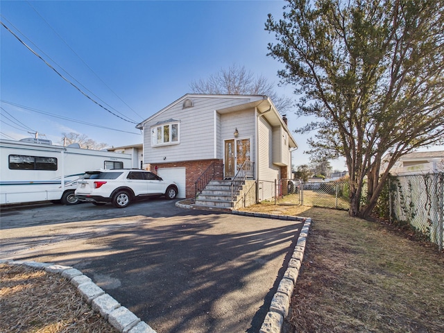 view of front facade featuring concrete driveway, brick siding, fence, and a gate