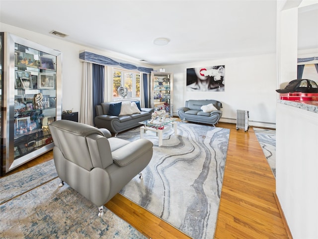 living room featuring a baseboard radiator, visible vents, and wood finished floors