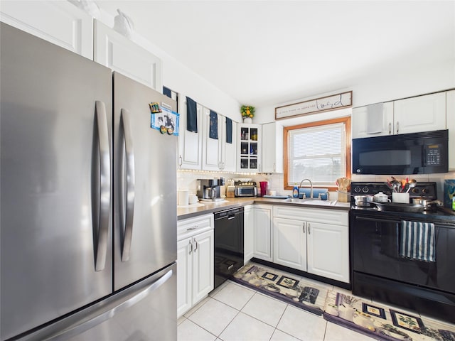 kitchen featuring decorative backsplash, white cabinetry, a sink, light tile patterned flooring, and black appliances