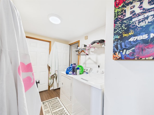 clothes washing area featuring washing machine and dryer, laundry area, and wood finished floors