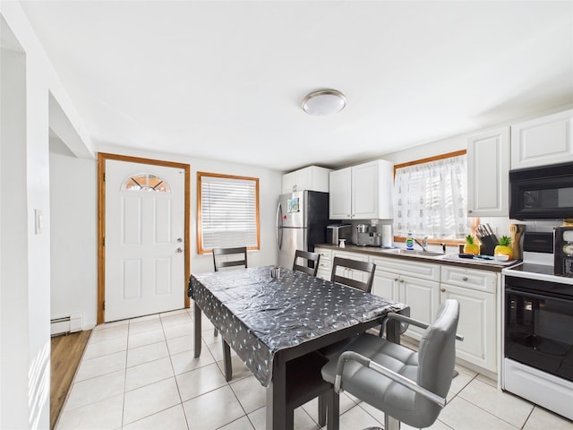 kitchen with range with electric stovetop, baseboard heating, freestanding refrigerator, a sink, and black microwave