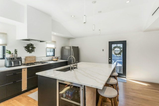 kitchen featuring beverage cooler, stainless steel appliances, a breakfast bar, a sink, and modern cabinets