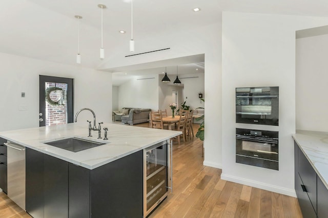 kitchen with light wood finished floors, beverage cooler, modern cabinets, open floor plan, and a sink