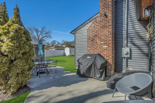 view of patio / terrace featuring an outbuilding, outdoor dining area, area for grilling, fence, and a shed