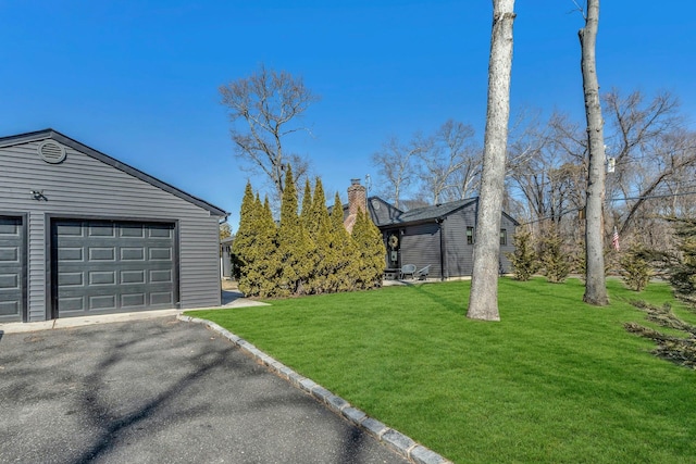 view of yard featuring a garage and aphalt driveway