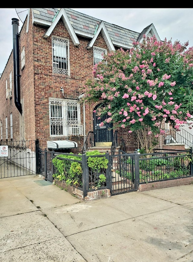 view of front facade featuring a high end roof, brick siding, and a gate