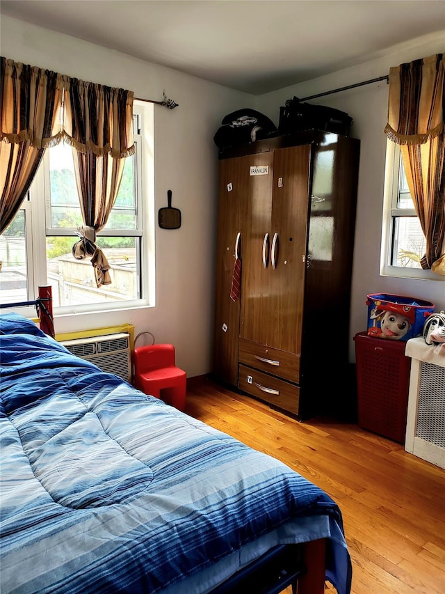 bedroom featuring an AC wall unit and light wood-style flooring