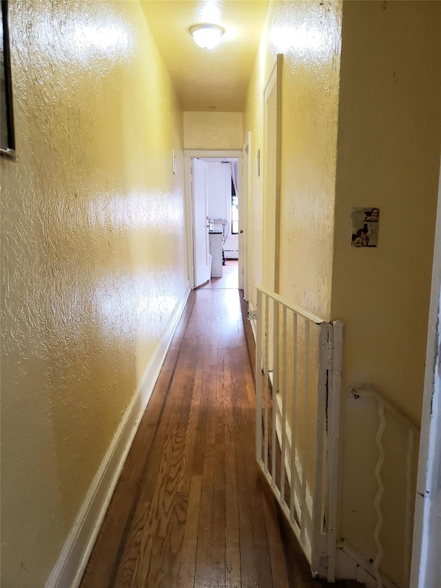 hallway featuring a textured wall and wood-type flooring