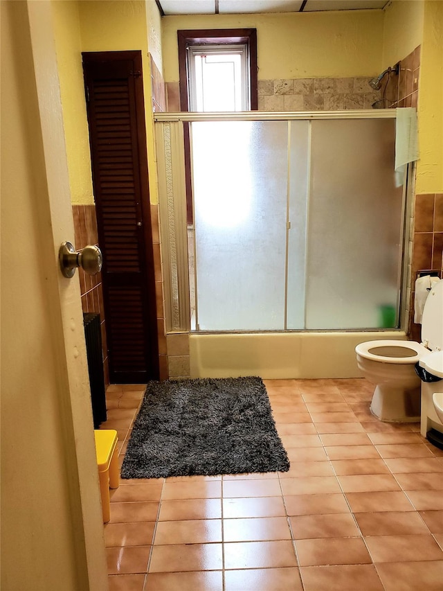 full bathroom featuring toilet, enclosed tub / shower combo, and tile patterned floors