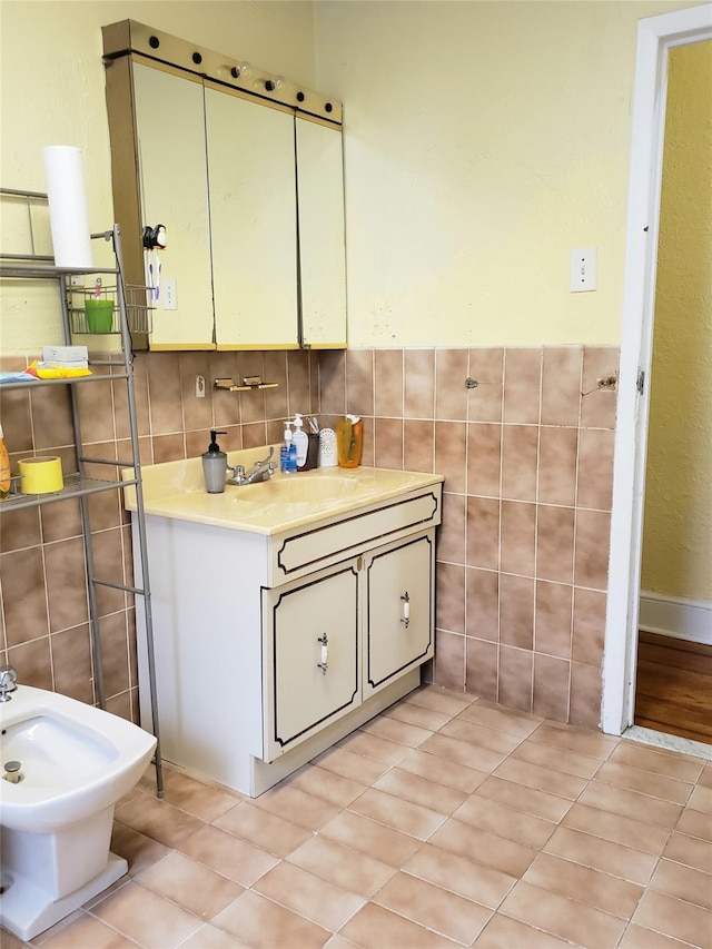 bathroom with a bidet, tile patterned flooring, vanity, and tile walls