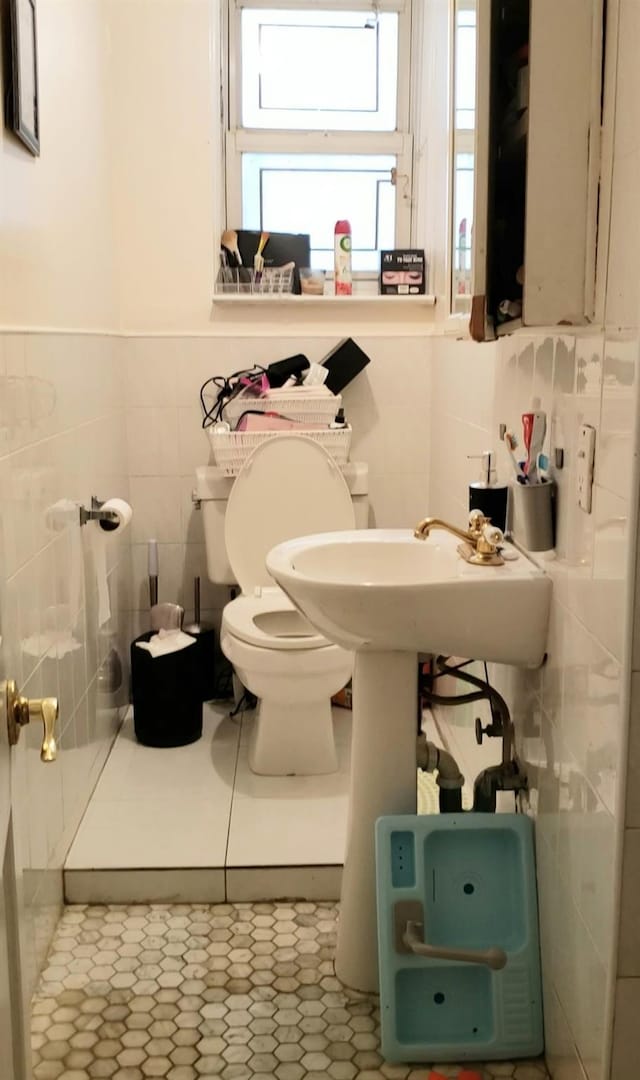 bathroom with tile patterned flooring, toilet, and tile walls