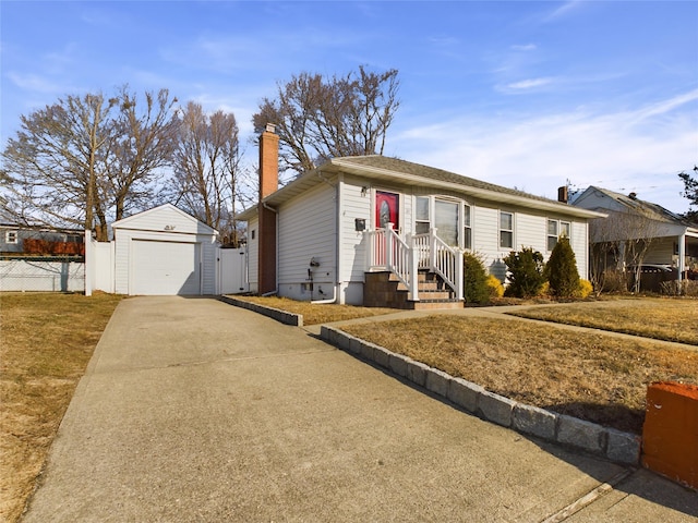 ranch-style home with concrete driveway, a chimney, a detached garage, fence, and an outdoor structure