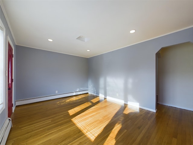 unfurnished room with arched walkways, hardwood / wood-style floors, and baseboard heating