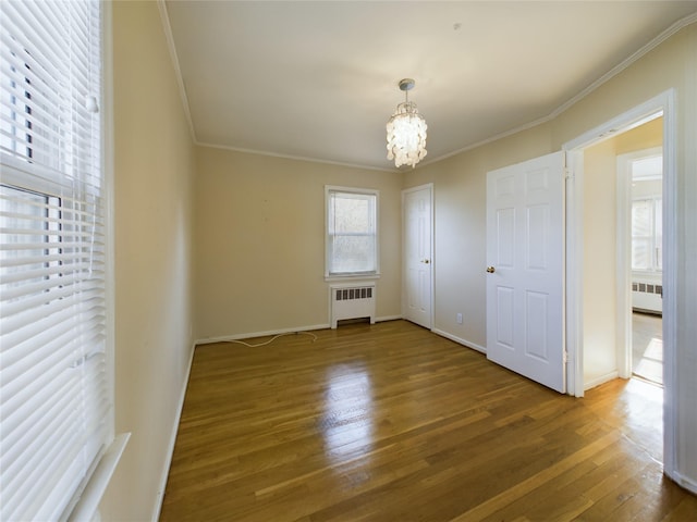 interior space with a notable chandelier, ornamental molding, wood finished floors, and radiator