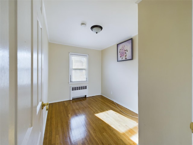 unfurnished room featuring baseboards, radiator heating unit, and hardwood / wood-style flooring