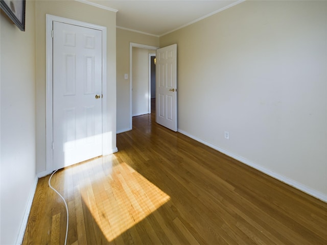 unfurnished bedroom with crown molding, baseboards, and wood finished floors