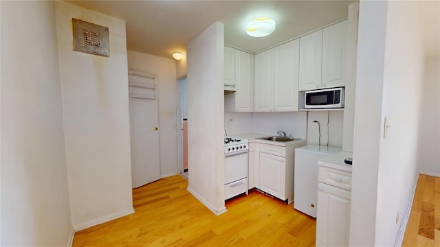 164-20 Highland Ave Unit 8W, Jamaica, NY 11432 - kitchen with white range with gas stovetop, light wood-style flooring, white cabinets, and light countertops