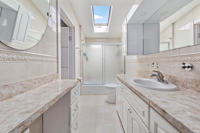 bathroom featuring enclosed tub / shower combo, a skylight, tile walls, and tile patterned floors