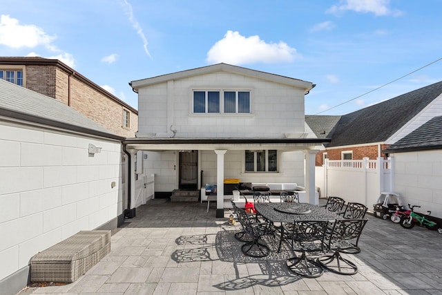 rear view of property with concrete block siding, outdoor dining area, entry steps, a patio area, and a fenced backyard