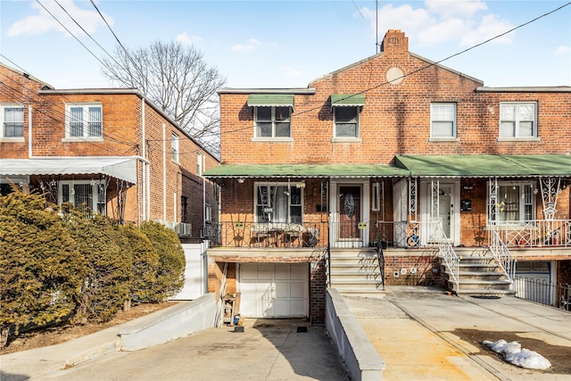 view of front of home featuring a porch, concrete driveway, brick siding, and an attached garage