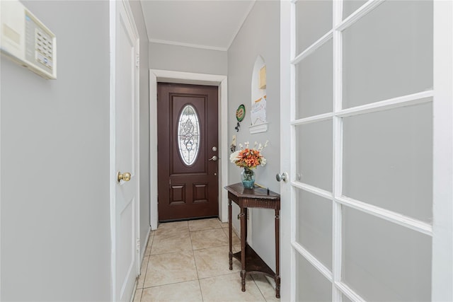 doorway to outside with ornamental molding and light tile patterned flooring