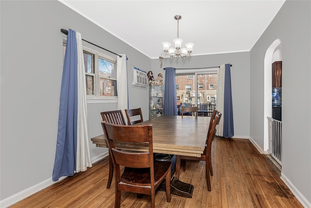 dining space featuring arched walkways, crown molding, wood finished floors, and a notable chandelier