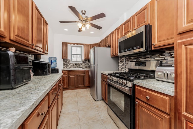 kitchen featuring light tile patterned floors, appliances with stainless steel finishes, decorative backsplash, and brown cabinets