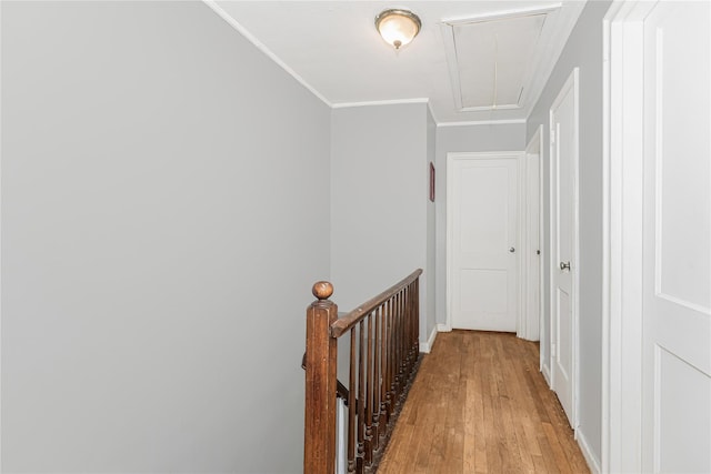 hallway featuring attic access, light wood-style floors, ornamental molding, an upstairs landing, and baseboards