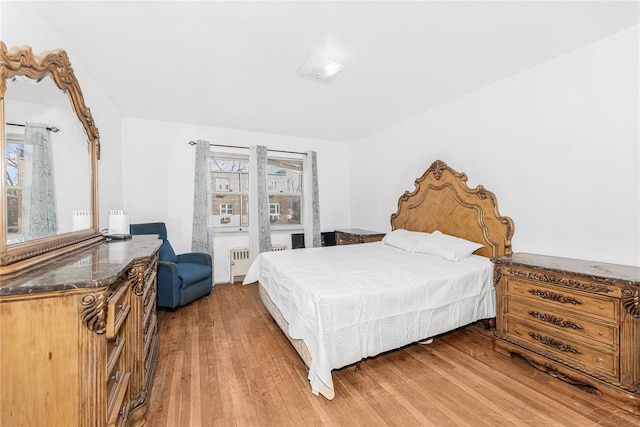 bedroom with radiator, multiple windows, and wood finished floors