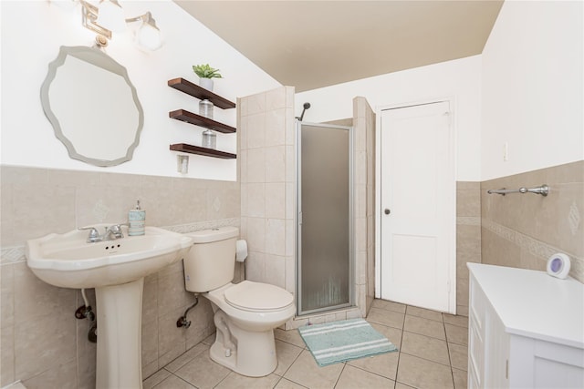 full bathroom with a stall shower, wainscoting, toilet, tile patterned flooring, and tile walls